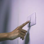 Mão desligando o interruptor apagando a luz. o que é consumo consciente de energia elétrica, sua importância e dicas de pequenas mudanças para economizar energia